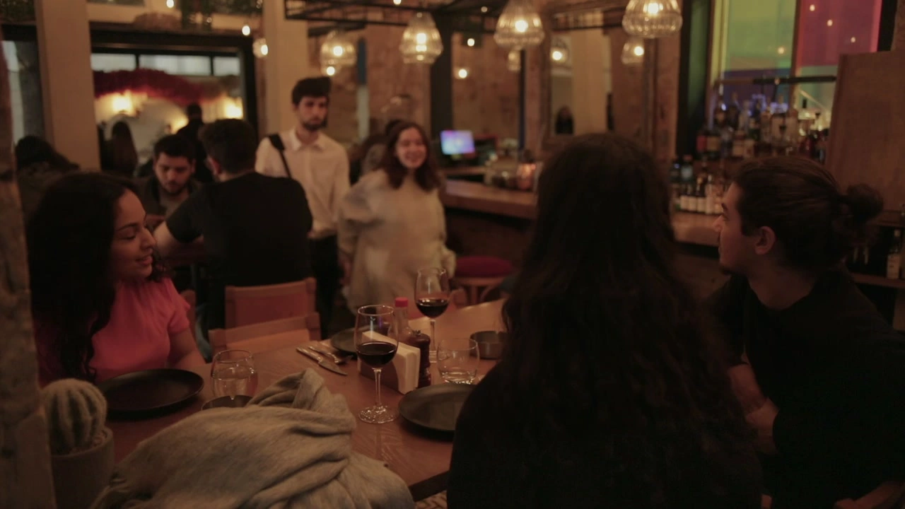 A group sits at a restaurant table beneath pendant lamps.