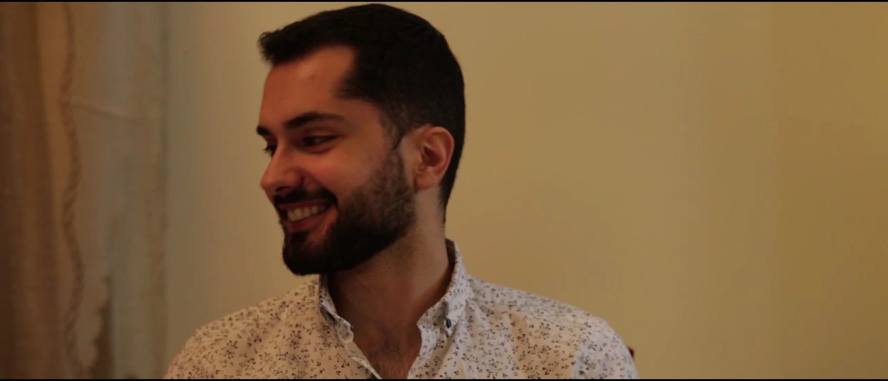 A man smiles in a warmly lit interior.