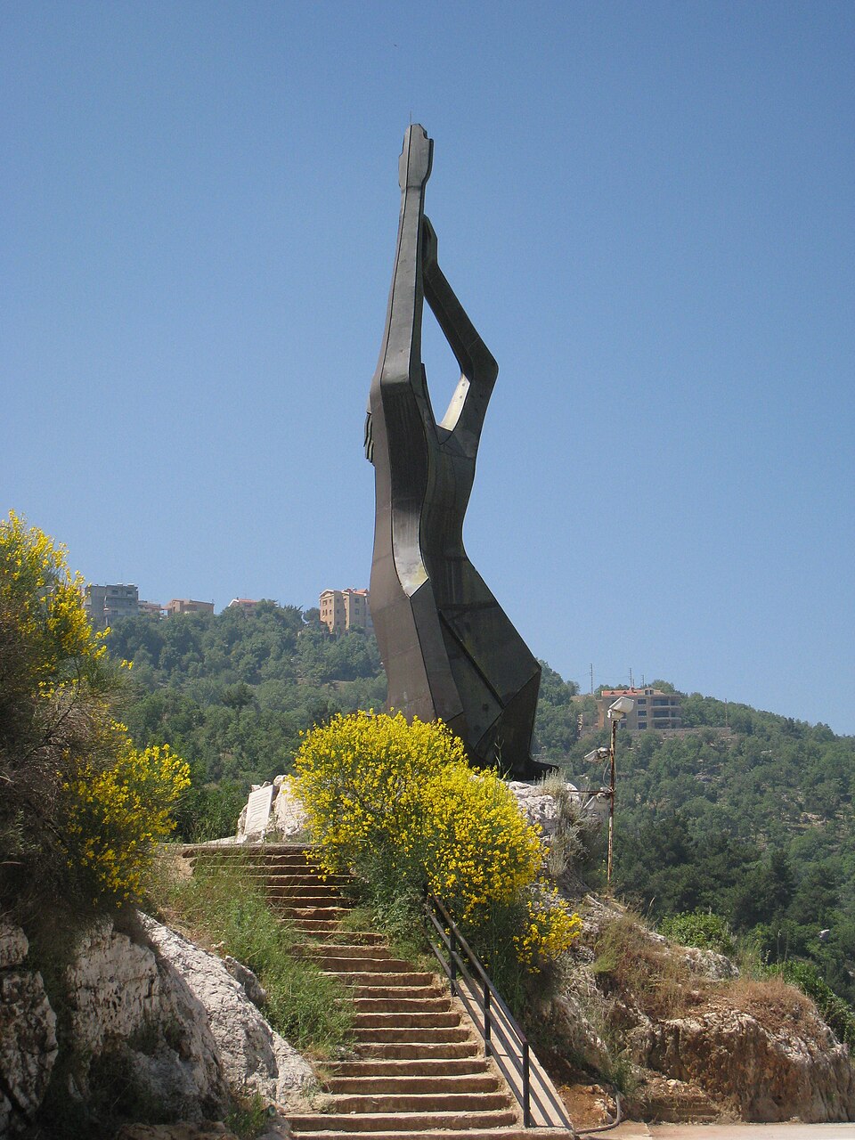 An angular memorial with an upward-reaching form above a flight of steps.