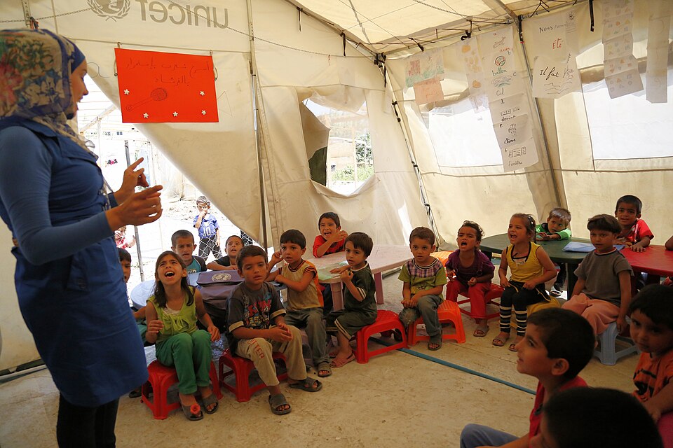Children seated for a lesson inside a temporary classroom.