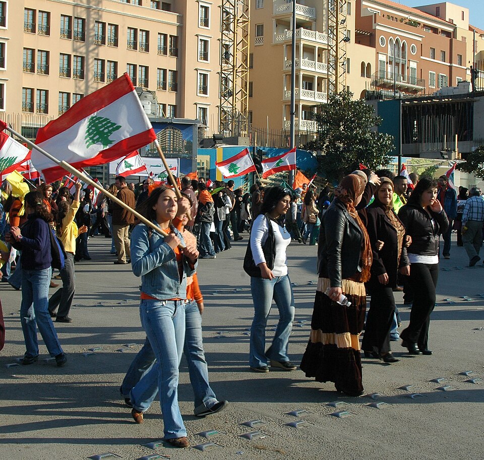 Women carrying Lebanese flags in a street demonstration.